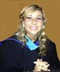 A young girl in a graduation gown smiles for the camera