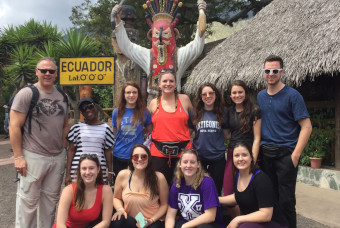 Group of people posing in front of &quot;Ecuador&quot; sign