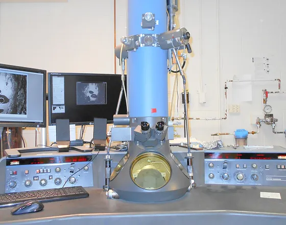 Image of a microscope on a table with equipment and screens