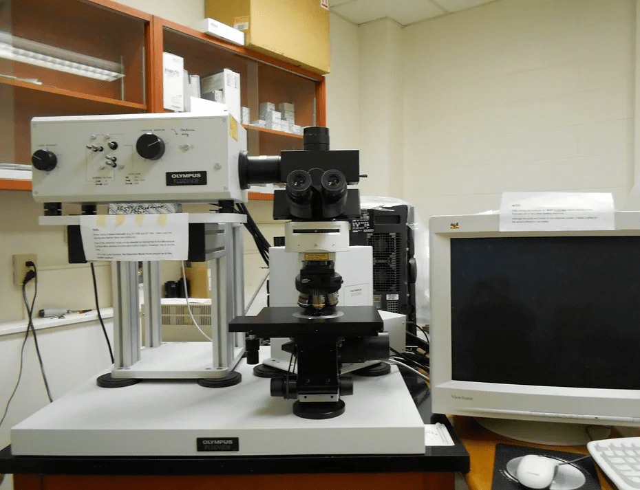 A microscope on a table with a monitor screen